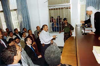 Shiia editor Abdulkarim Al-Khaiwani watches from behind bars as his lawyer argues with the judge during an appeals court session in Sanaa, Yemen, in March.